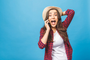 Amazed woman keeping mouth wide open, looking surprised, talking on mobile phone, conducting pleasant conversation isolated on blue background. People sincere emotions, lifestyle. Mock up copy space.