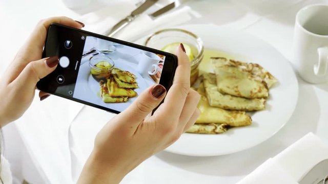 Pancakes and apple jam. Female hands taking photo of breakfast food by smartphone. 4K