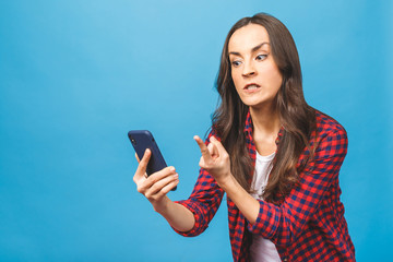 Portrait of a furious young business woman yelling at mobile phone isolated over blue background.