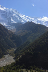 Naklejka premium colossal snowy peaks peeking out from behind the hills covered with trees. annapurna travel