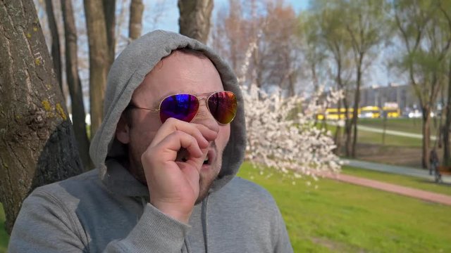 Uncultured man in sunglasses with bad manners picks his nose, disgraceful and shocking behaviour