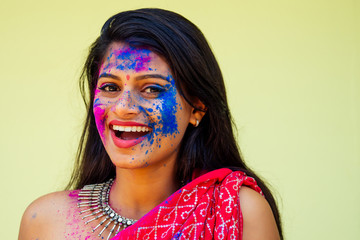 Holi Festival Of Colours. Portrait of happy indian girl in traditional hindu sari on holi color . india woman silver jewelry with powder paint on dress ,colorful pink and blue hair in Goa Kerala