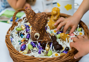 many children hands reach for sweets candy and chocolate in an Easter egg basket during Easter