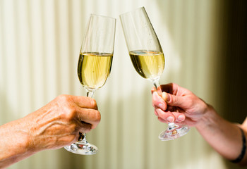 hand of eldery woman and young woman toasting with glasses of champagne