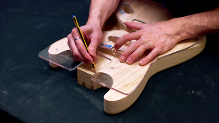 Obraz na płótnie Canvas Guitar maker draw guitar shape on wood