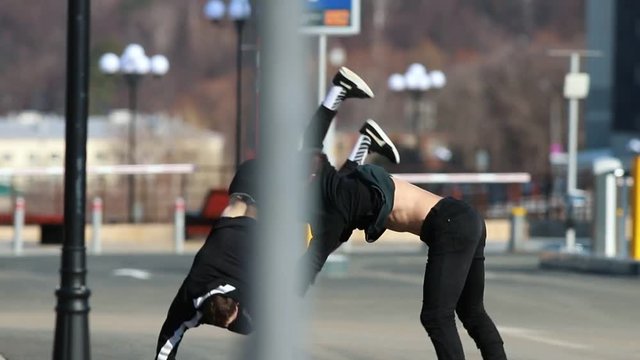 Two young men performing acrobatic parkour tricks and somersault in the end
