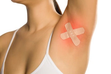 woman posing with adhesive plaster on her armpit on white background