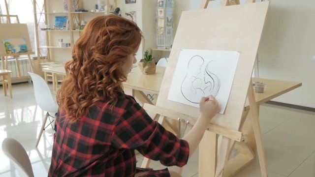 Young pregnant girl draws with pencil in art Studio