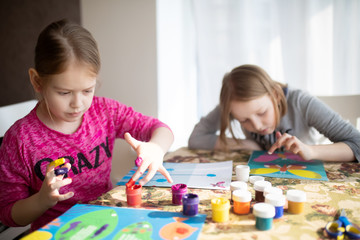 Fototapeta premium Two sisters little girls drawing with fingers on paper. Play, fun, childhood. Montessori school