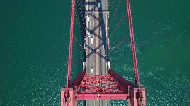 Aerial, top down, drone shot, above cars and trucks, on road A2 and the 25 of April or the Salazar bridge, on a sunny day, on Tejo river, in Lisbon, Portugal