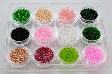 Set of multicolored beads for embroidery and needlework in plastic jars