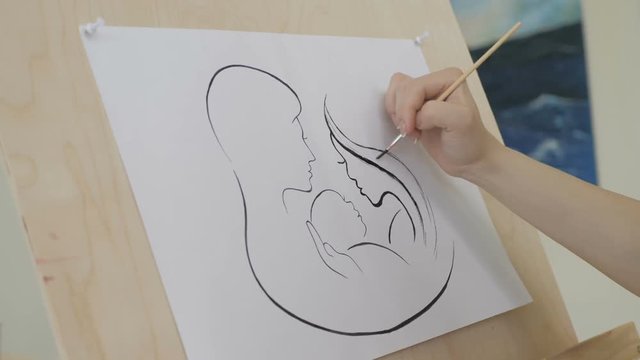 The girl's hand draws a picture with a pencil on white paper
