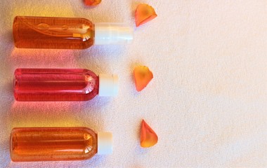 Shower gels in clear bubbles and rose petals on a white towel. Everything for baths and saunas.