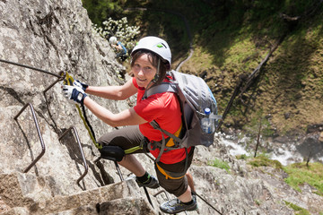 Woman climbing on rock via ferrata towards Lehner Waterfall, Otztal, Tyrol, Austria