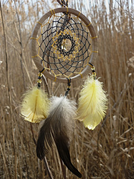 Dream catcher with yellow feathers on the background of reeds. Dreamcatcher sunset, mountains, boho-chic, ethnic amulet, symbol.