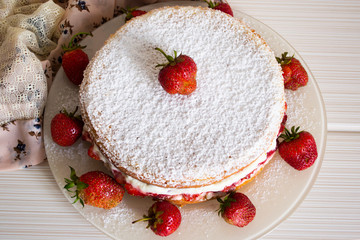Strawberry cake with whipped cream, fresh strawberries and with powdered sugar