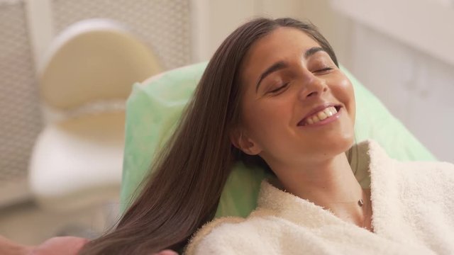 Young Caucasian Female Patient Laying Down While Her Hair Mesotherapy Specialist Sprays Her Hair. Light Camera Movement
