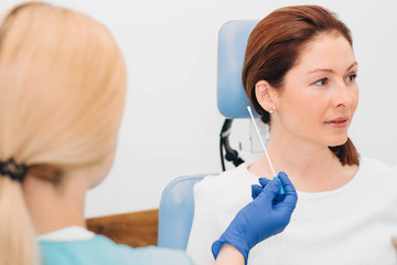 doctor checking patient's ear, woman while ear exam