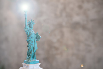 Statue of liberty WITH len flare effect on torch in the right hand on Concrete Polishing wall background and copy text space.