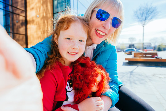 Family couple mature mother in blue eyeglasses and her preschooler red hair daughter together in outdoor activity hugging and enjoying the day before back to school. blonde caucasian mom and girl.
