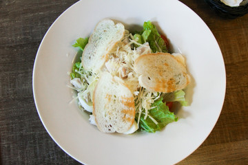 Close-up view of delicious Caesar salad on wooden table in cafe