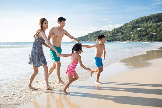 Happy young family running on beach