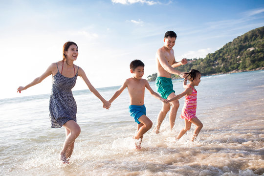 Happy young family running on beach