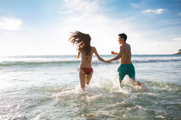 Happy young couple running in sea water