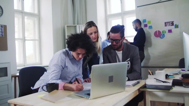 Group of young businesspeople with computer working together in a modern office.