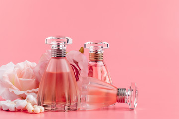 Perfume bottle with roses on pink fabric background