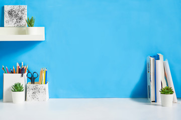 office creative desk with supplies, and blue wall.