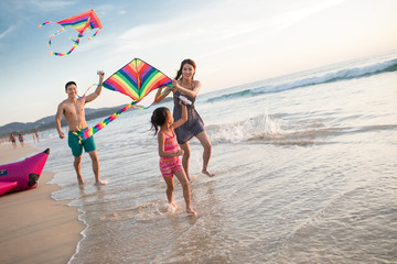 Happy young family flying a kite on beach