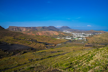 Spain, Lanzarote, Scenic aerial view over valley of volcanoes to town haria full of green palms