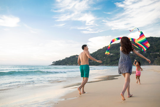 Happy young family flying a kite on beach
