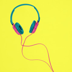 Pink and blue headphones on a yellow background. Minimal music concept with copy space.