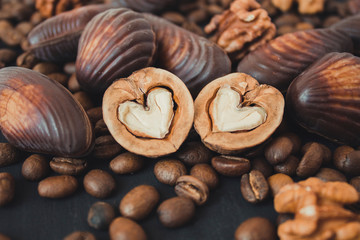  Nuts, chocolate and coffee on a black background. Walnuts in the shape of a heart. Sweets and nuts