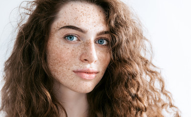 Beautiful Freckles young woman close up portrait. Attractive model with beautiful blue eyes and...