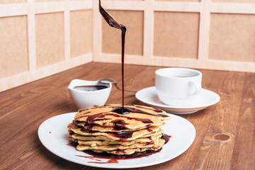 Pancakes with cherry syrup. Tea. Wooden table.