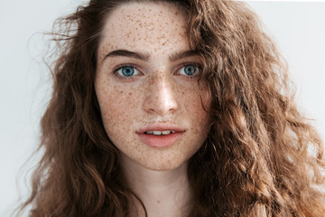 Beautiful Freckles young woman close up portrait. Attractive model with beautiful blue eyes and ginger curly hair - Powered by Adobe