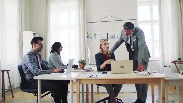 Group of young and old businesspeople with laptop working together in office.