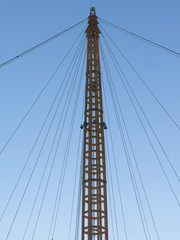 Silhouette of mast and rigging agains blue morning sky.