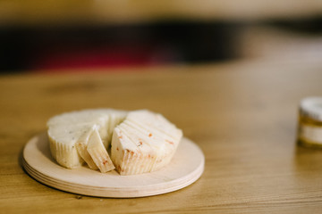 Pieces of cheese lie on a wooden tray on the table