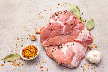 Raw pork shoulder with spices. Bay leaf, garlic. On a stone background, close up.