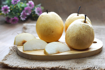 Fresh golden pear  on cutting board with flower background