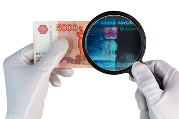 Investigeting counterfeit money. Hands in white gloves with x ray magnifier over 5000 rubles banknote isolated on white background