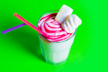milkshake with a straw and marshmallows on a green background