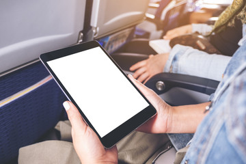 Mockup image of a woman holding and looking at black tablet pc with blank white desktop screen while sitting in the cabin