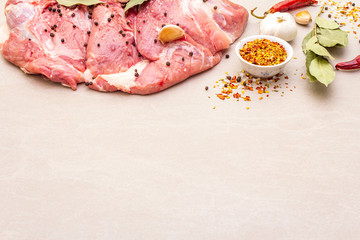 Raw pork shoulder with spices. Bay leaf, garlic. On a stone background, copy space.