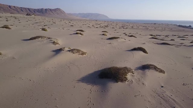 Las Tortolas beach aerial footage at Atacama Desert the sunset ray lights illuminate this amazing and idyllic beach in the middle of the desert, an arid awe landscape crashed by Pacific Ocean waters
