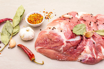 Raw pork shoulder with spices. Bay leaf, garlic. On a stone background, close up.